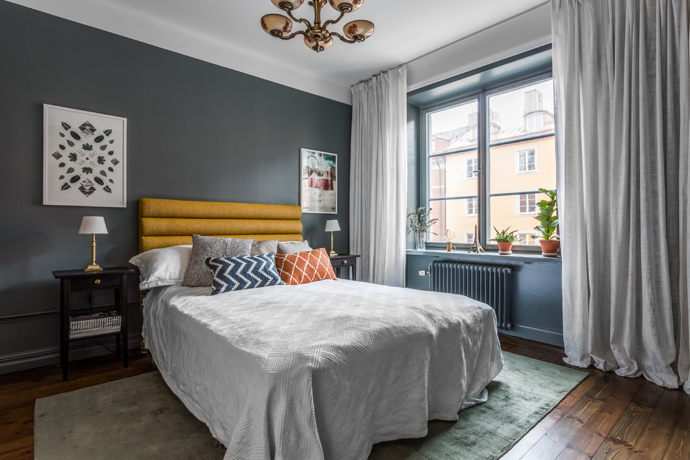 Cette photo montre une chambre parentale tendance de taille moyenne avec un mur gris, parquet foncé, aucune cheminée et un sol marron.