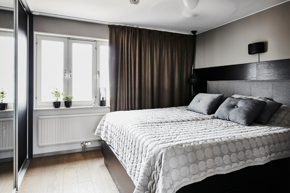 This is an example of a medium sized contemporary master bedroom in Gothenburg with beige walls, light hardwood flooring, no fireplace and brown floors.