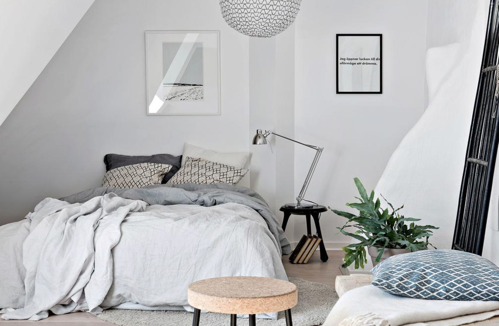 This is an example of a medium sized scandinavian master bedroom in Gothenburg with white walls and light hardwood flooring.