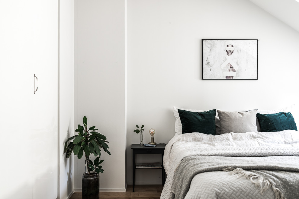 Mittelgroßes Nordisches Hauptschlafzimmer mit weißer Wandfarbe und braunem Holzboden in Stockholm