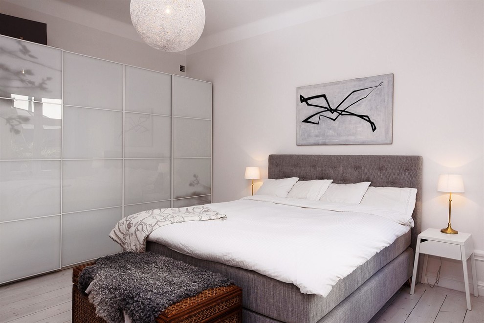 Diseño de dormitorio principal contemporáneo de tamaño medio sin chimenea con paredes blancas y suelo de madera clara
