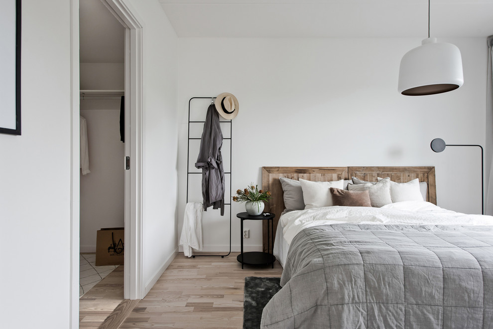 Foto di una camera matrimoniale scandinava con pareti bianche, parquet chiaro e pavimento beige