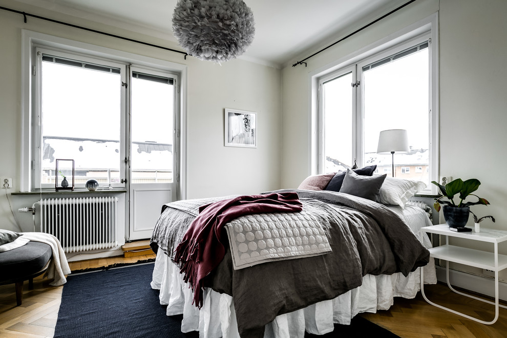 Mittelgroßes Nordisches Hauptschlafzimmer mit weißer Wandfarbe, braunem Holzboden und beigem Boden in Stockholm