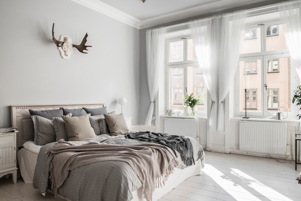 Skandinavisches Schlafzimmer mit weißer Wandfarbe, gebeiztem Holzboden und weißem Boden in Stockholm