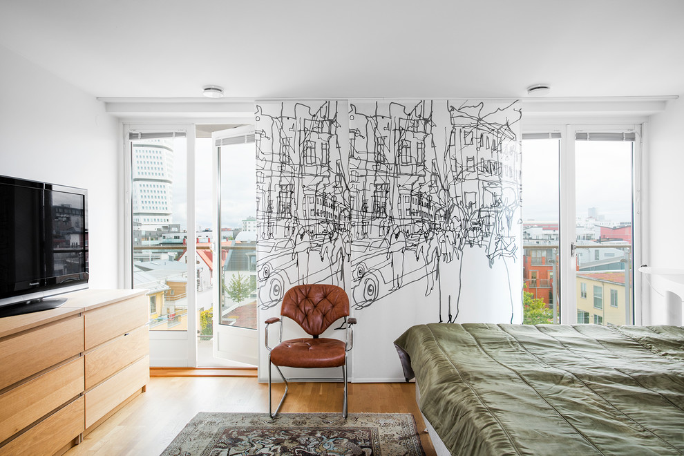 Diseño de dormitorio principal y televisión actual con paredes blancas y suelo de madera en tonos medios