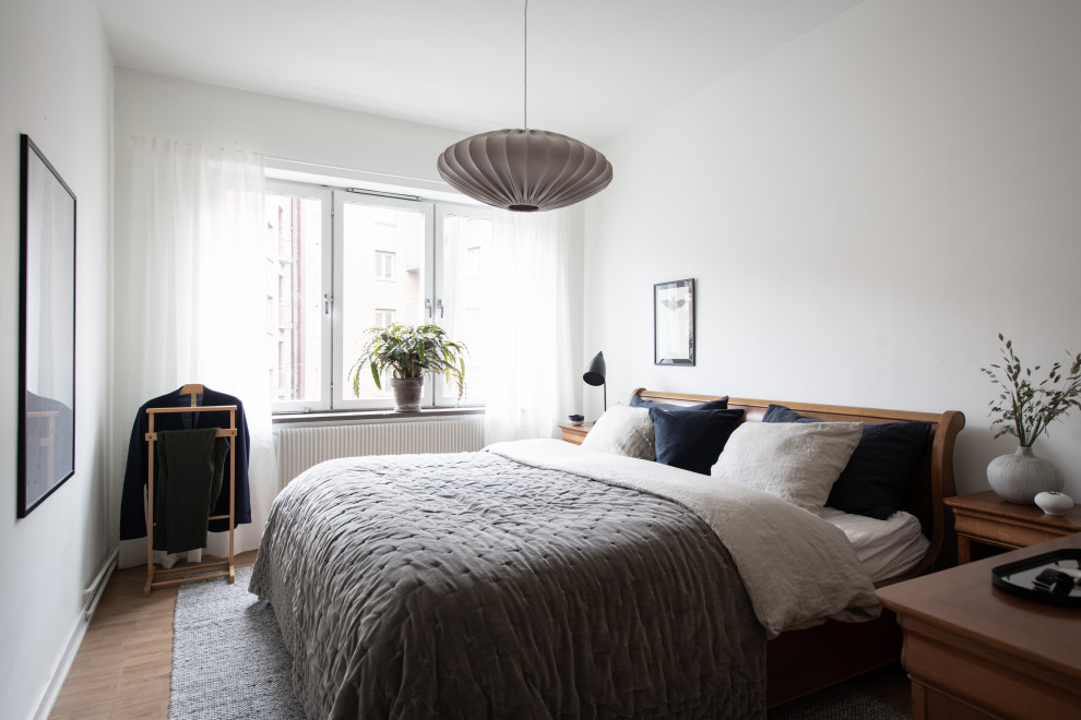 Design ideas for a contemporary bedroom in Gothenburg with white walls, medium hardwood flooring and brown floors.