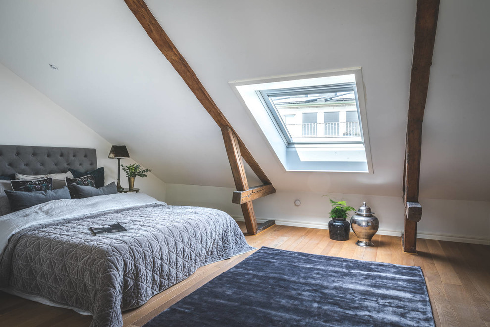 Bild på ett minimalistiskt sovrum, med vita väggar, mellanmörkt trägolv och brunt golv