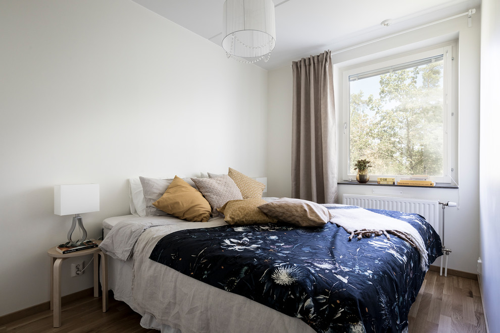 ストックホルムにある中くらいな北欧スタイルのおしゃれな主寝室 (白い壁、無垢フローリング、茶色い床)
