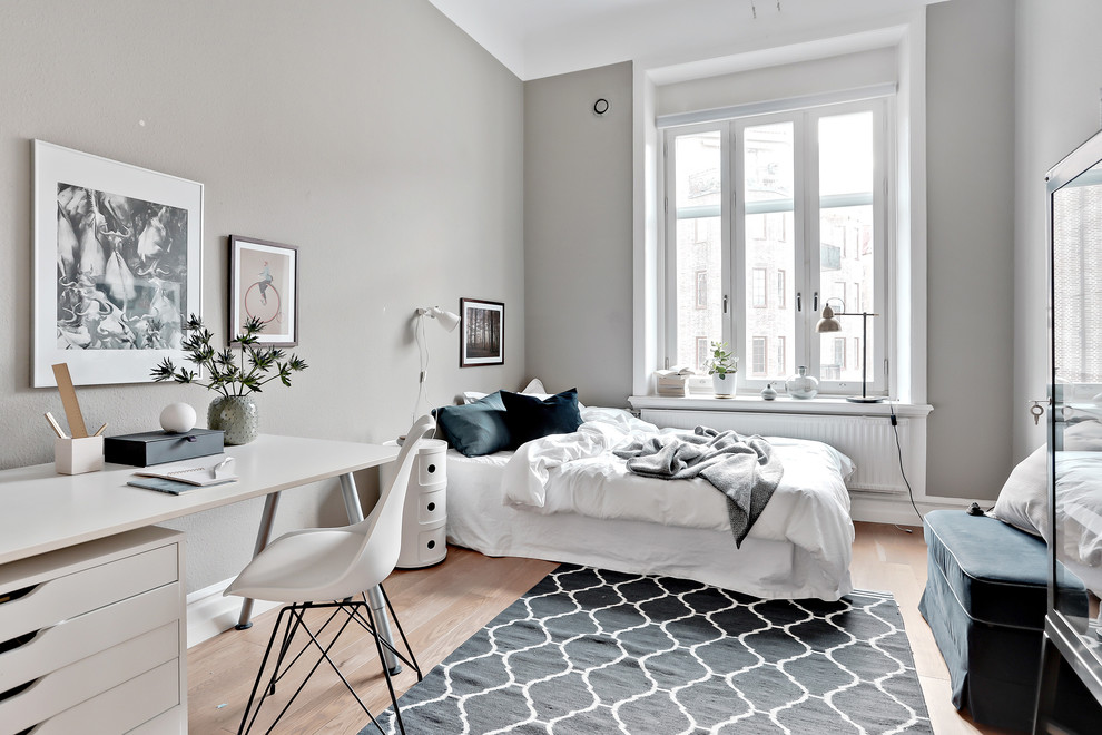 Cette photo montre une grande chambre d'amis scandinave avec un mur gris, parquet clair, aucune cheminée et un sol beige.