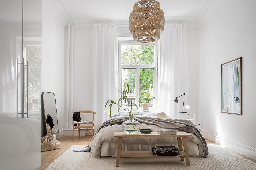 Bild på ett minimalistiskt sovrum, med vita väggar, ljust trägolv och beiget golv