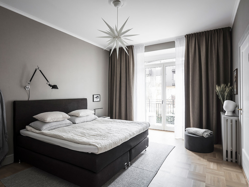 Mittelgroßes Nordisches Hauptschlafzimmer mit grauer Wandfarbe, braunem Holzboden und beigem Boden in Göteborg