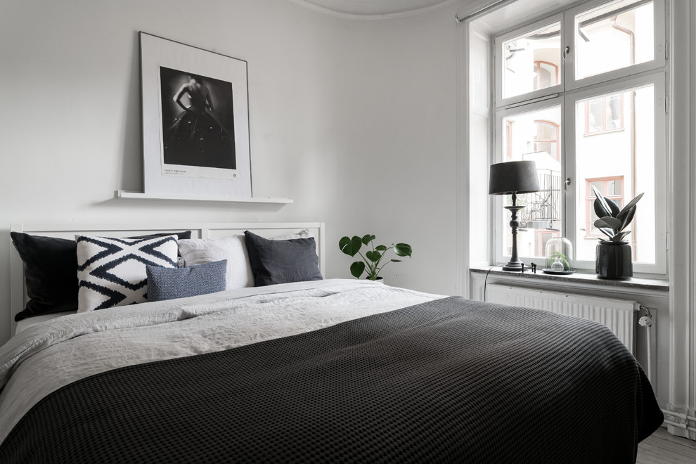 This is an example of a scandinavian guest bedroom in Stockholm with white walls, light hardwood flooring and beige floors.