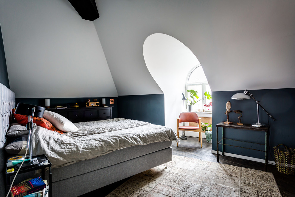 Photo of a scandi bedroom in Stockholm with black walls and dark hardwood flooring.