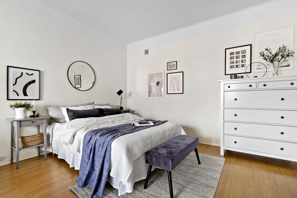 Foto på ett minimalistiskt sovrum, med vita väggar och mellanmörkt trägolv