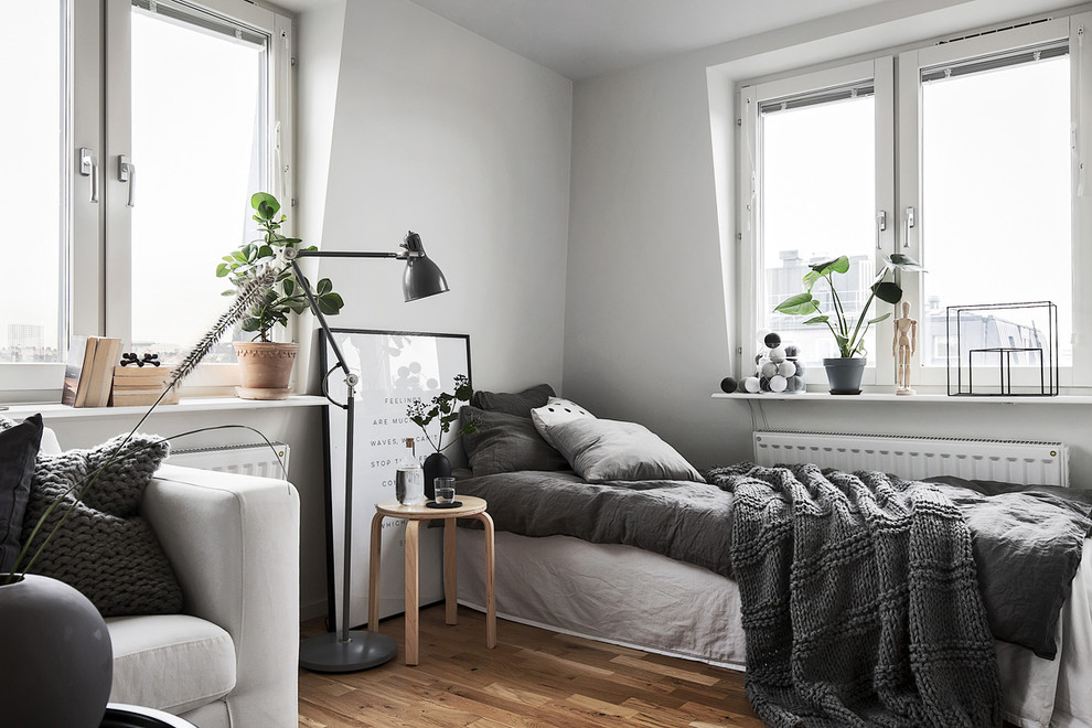 Ejemplo de habitación de invitados nórdica de tamaño medio con paredes blancas y suelo de madera en tonos medios