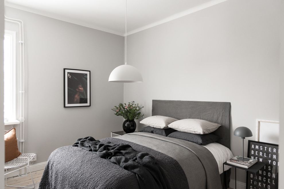 Ejemplo de dormitorio gris y negro escandinavo con paredes grises, suelo de madera clara y suelo beige