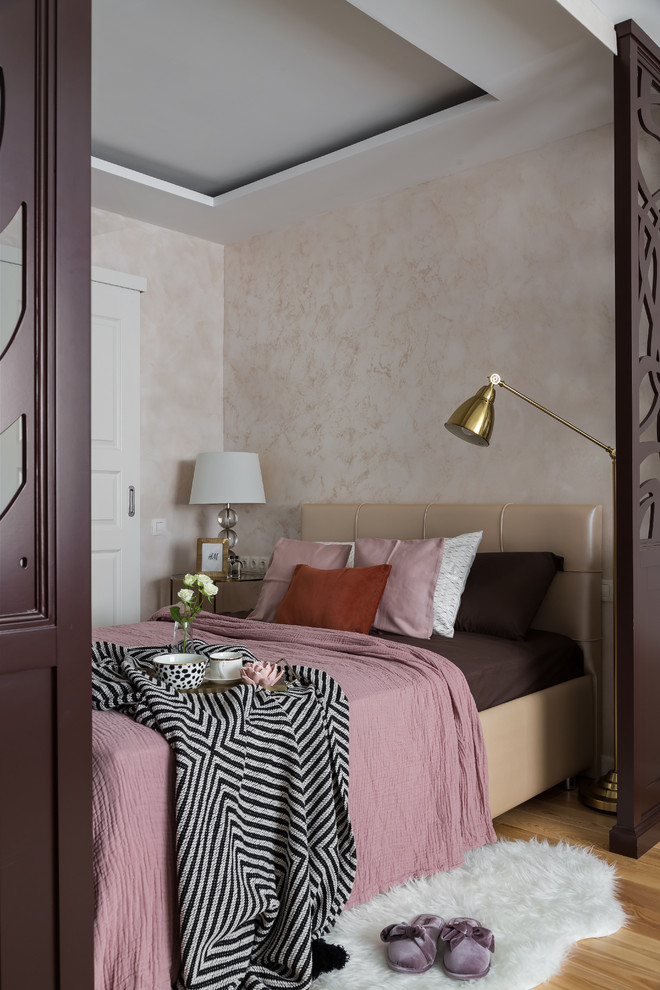Cette photo montre une chambre parentale tendance avec un mur beige, un sol en bois brun et aucune cheminée.