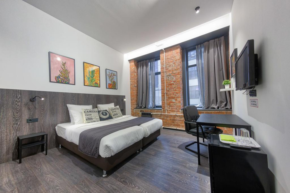 Ejemplo de habitación de invitados urbana de tamaño medio con paredes blancas, suelo laminado y suelo gris