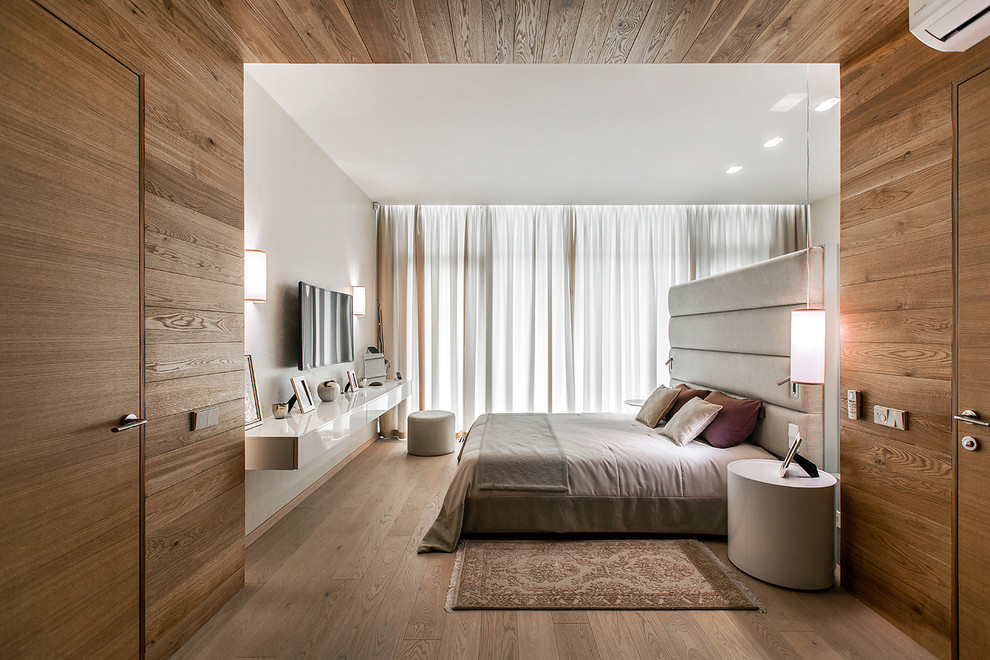 Ejemplo de dormitorio principal y televisión contemporáneo grande con suelo de madera clara