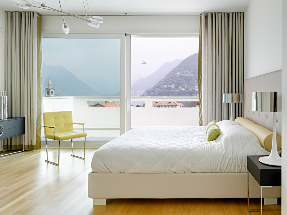 Großes Modernes Hauptschlafzimmer mit weißer Wandfarbe und braunem Holzboden in Mailand