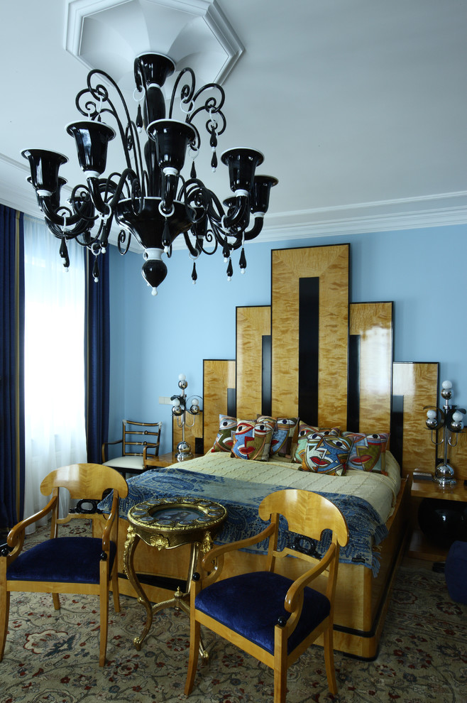 Modelo de dormitorio principal tradicional de tamaño medio con paredes azules, suelo de madera clara, chimenea lineal, marco de chimenea de piedra y suelo beige