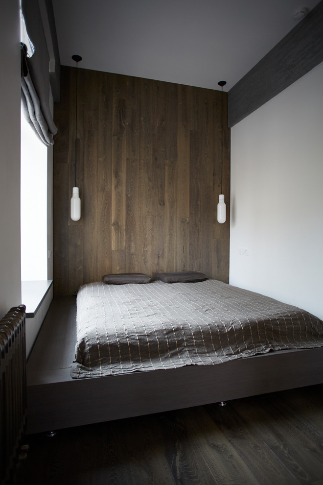 Réalisation d'une chambre parentale minimaliste avec un mur blanc, parquet foncé et un sol gris.