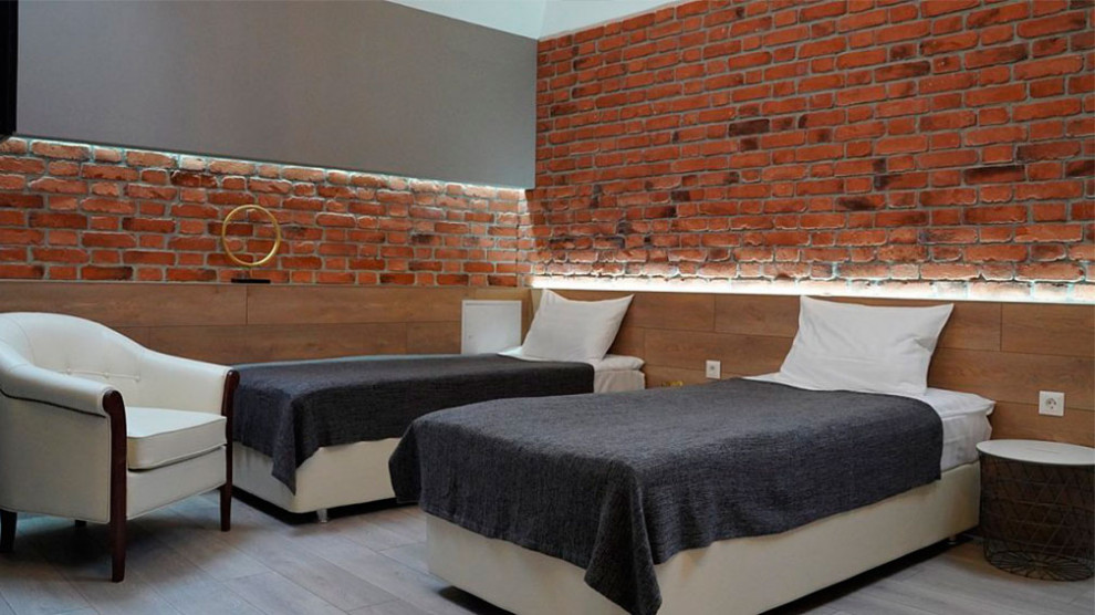 На фото: гостевая спальня среднего размера, (комната для гостей) в стиле лофт с красными стенами, полом из керамогранита, фасадом камина из кирпича и бежевым полом без камина с