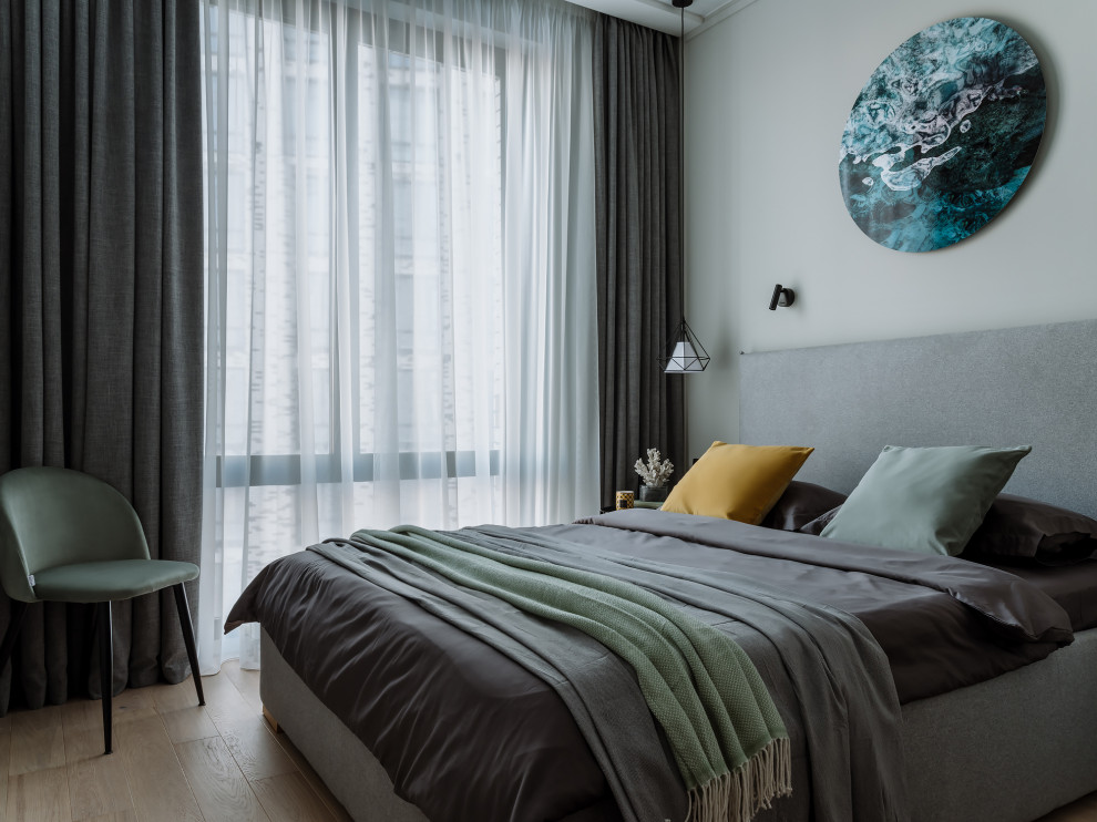 Modelo de dormitorio contemporáneo con paredes grises, suelo de madera clara y suelo beige
