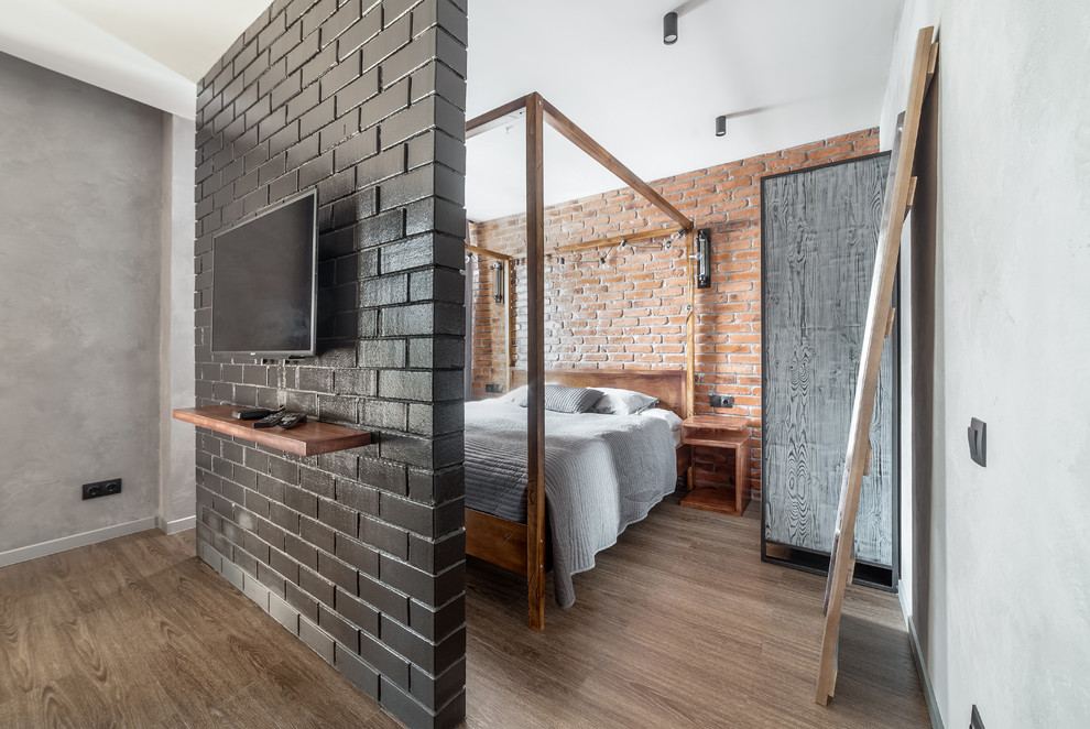 Immagine di una camera da letto industriale con pavimento in legno massello medio, pavimento marrone e pareti grigie