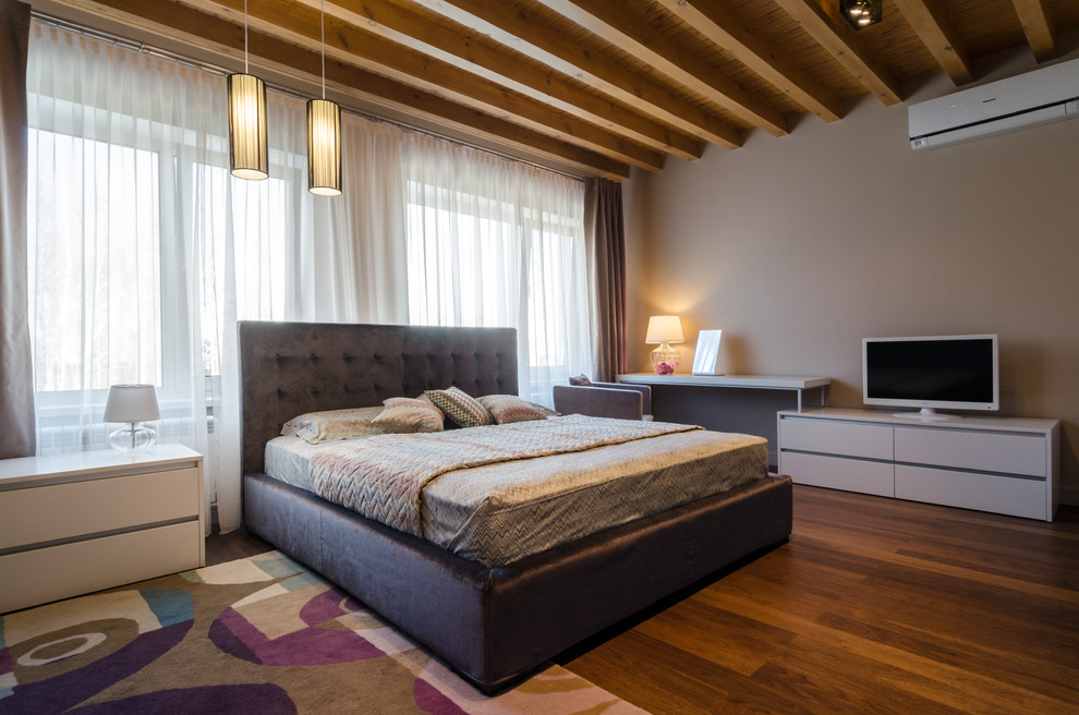 Cette photo montre une chambre tendance avec un mur gris et un sol en bois brun.