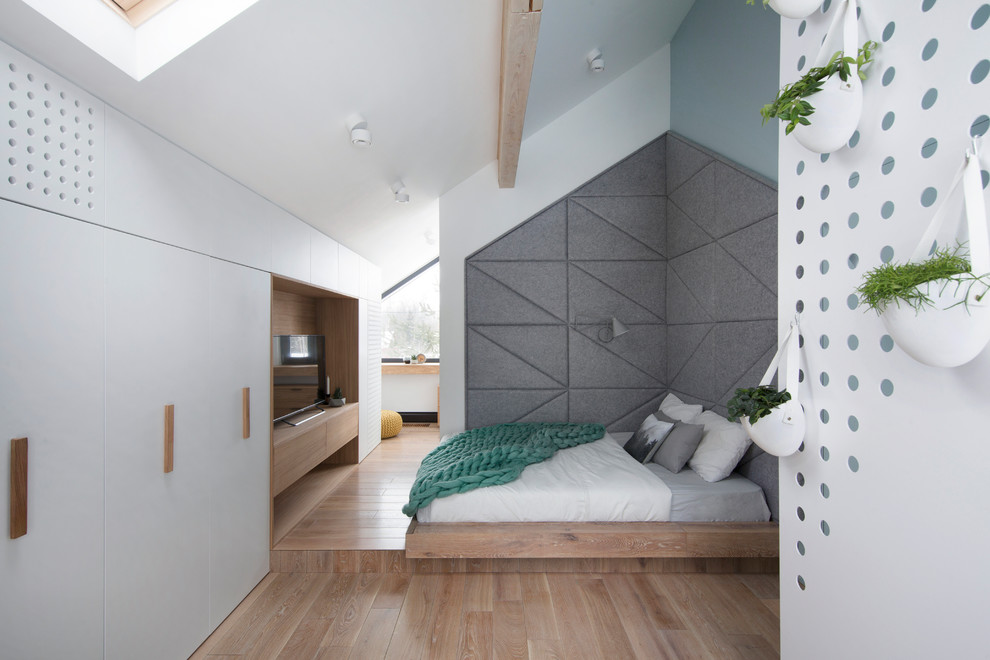 Modelo de dormitorio principal contemporáneo con paredes blancas, suelo de madera en tonos medios, suelo marrón y techo inclinado