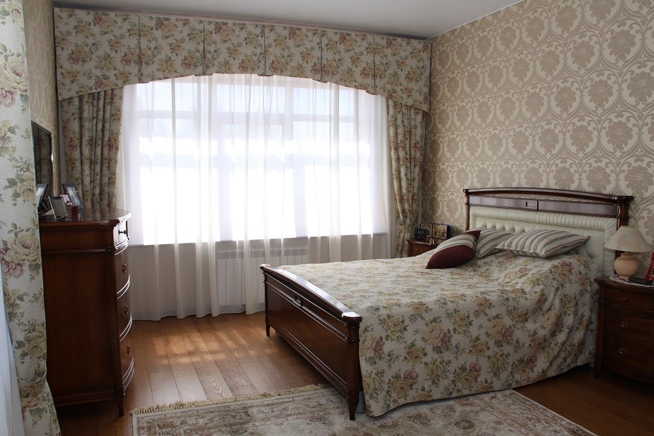 Modelo de dormitorio principal de estilo de casa de campo pequeño con paredes beige y suelo de madera oscura