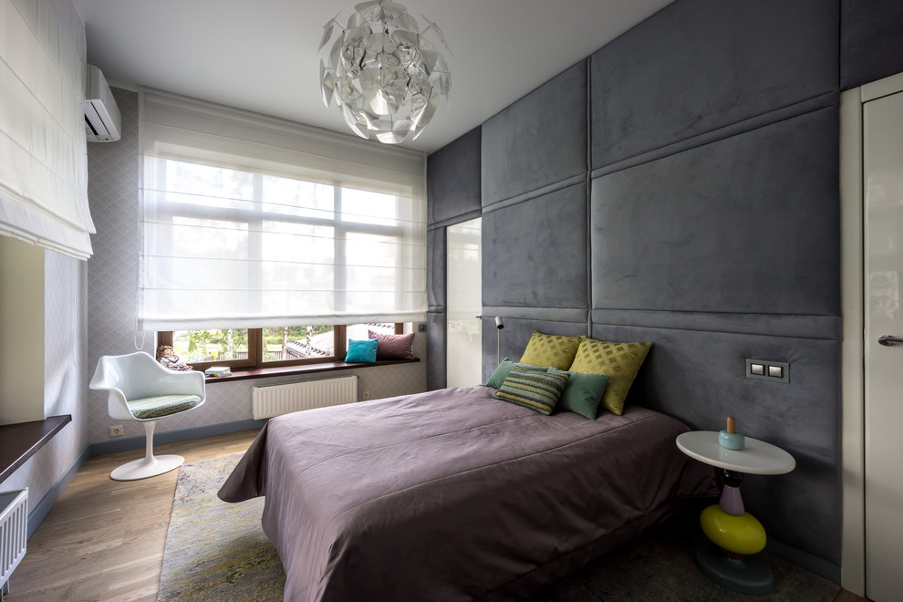 Imagen de dormitorio principal contemporáneo de tamaño medio con suelo de madera clara y paredes grises