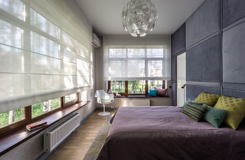 Modelo de dormitorio principal contemporáneo con paredes grises y suelo de madera en tonos medios