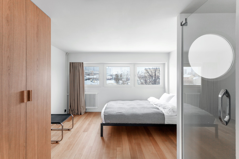 This is an example of a small contemporary master bedroom in Moscow with white walls and medium hardwood flooring.