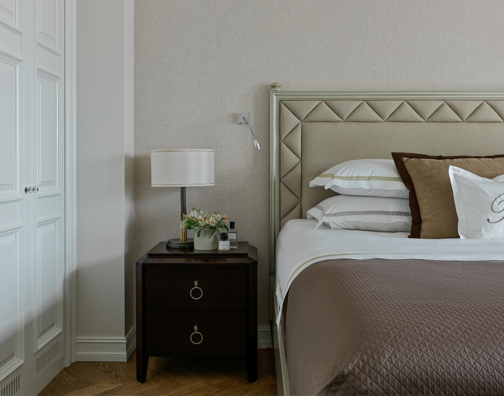 Modelo de dormitorio principal clásico de tamaño medio con paredes beige, suelo de madera clara y suelo marrón