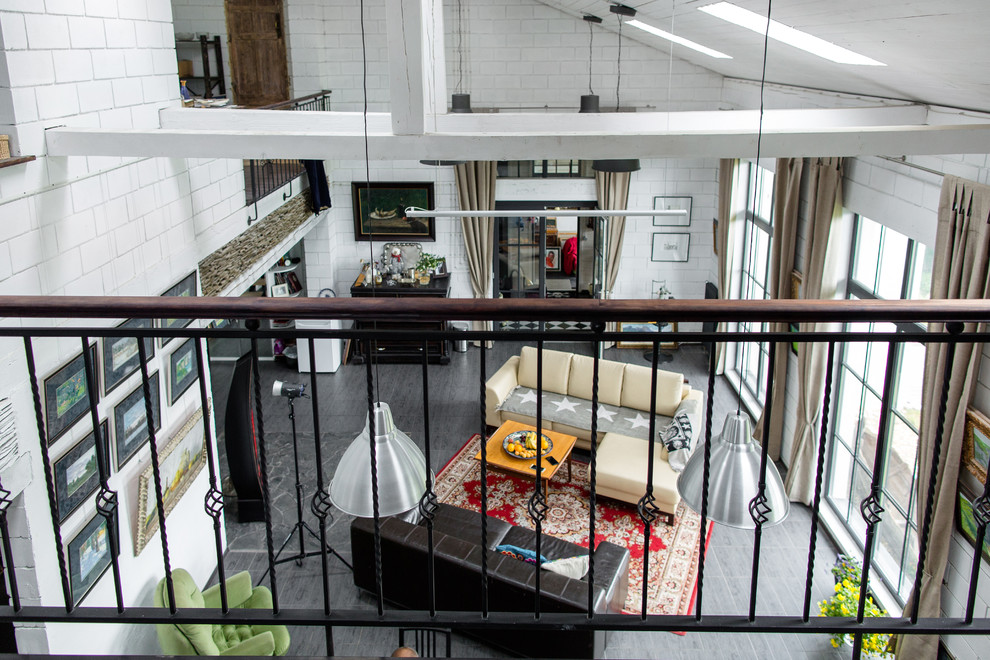 Aménagement d'une chambre mansardée ou avec mezzanine industrielle avec un mur blanc et parquet foncé.