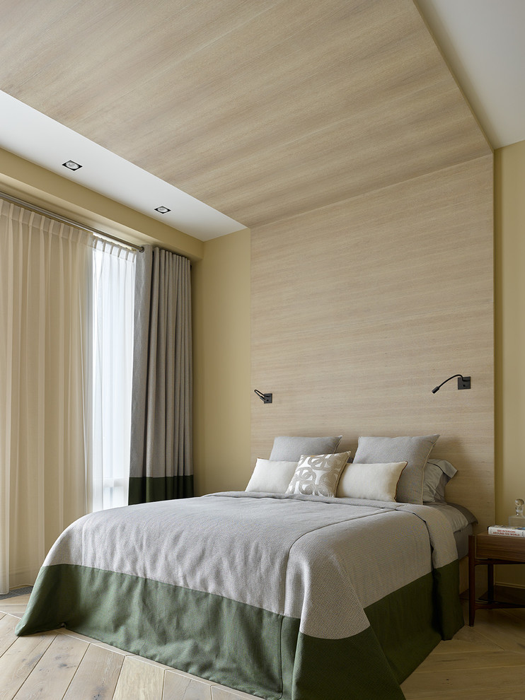 Immagine di una camera matrimoniale design con parquet chiaro, pavimento beige e pareti gialle