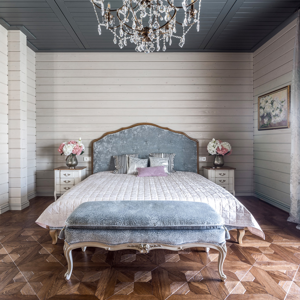 他の地域にある広いトランジショナルスタイルのおしゃれな主寝室 (グレーの壁、無垢フローリング、茶色い床) のインテリア