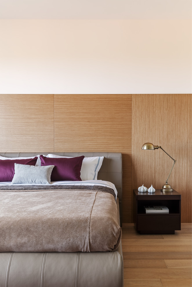 Modelo de dormitorio principal actual de tamaño medio sin chimenea con paredes blancas, suelo de madera en tonos medios y suelo beige