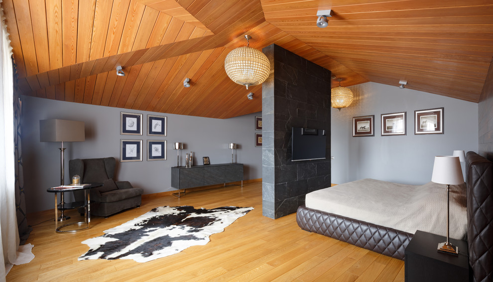На фото: хозяйская спальня на мансарде в современном стиле с серыми стенами и паркетным полом среднего тона с