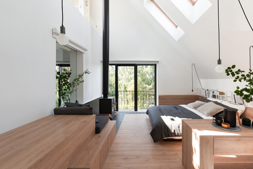 Imagen de dormitorio actual con paredes blancas, suelo de madera en tonos medios, estufa de leña y suelo marrón