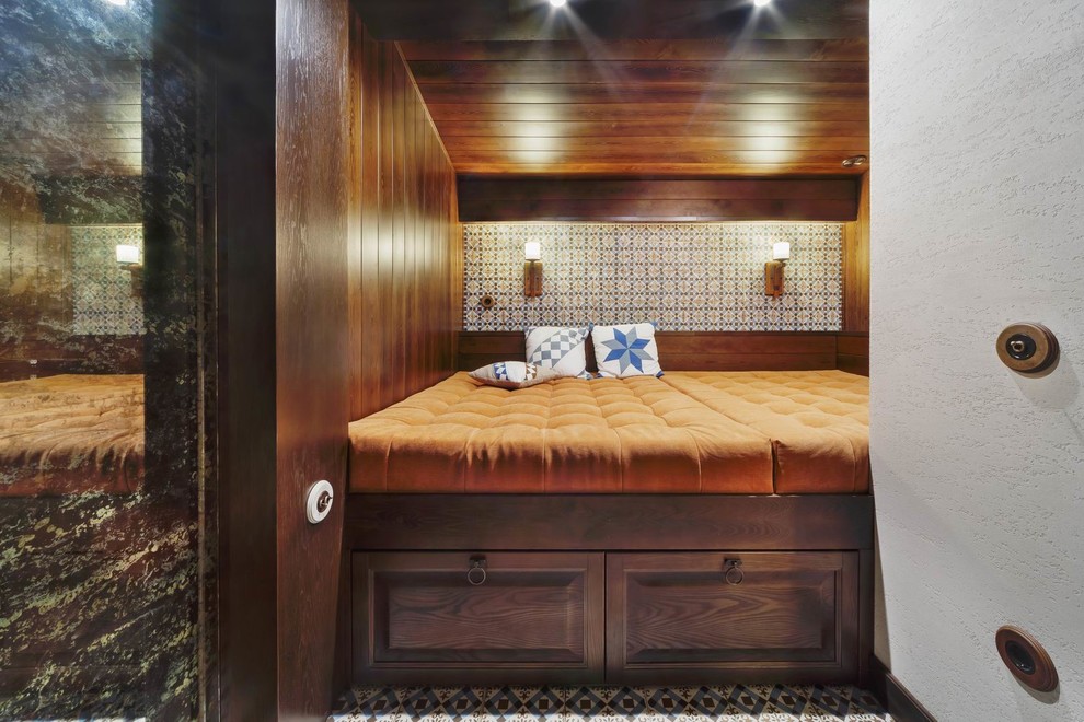 На фото: гостевая спальня (комната для гостей) в стиле фьюжн с коричневыми стенами, полом из керамогранита, разноцветным полом и кроватью в нише