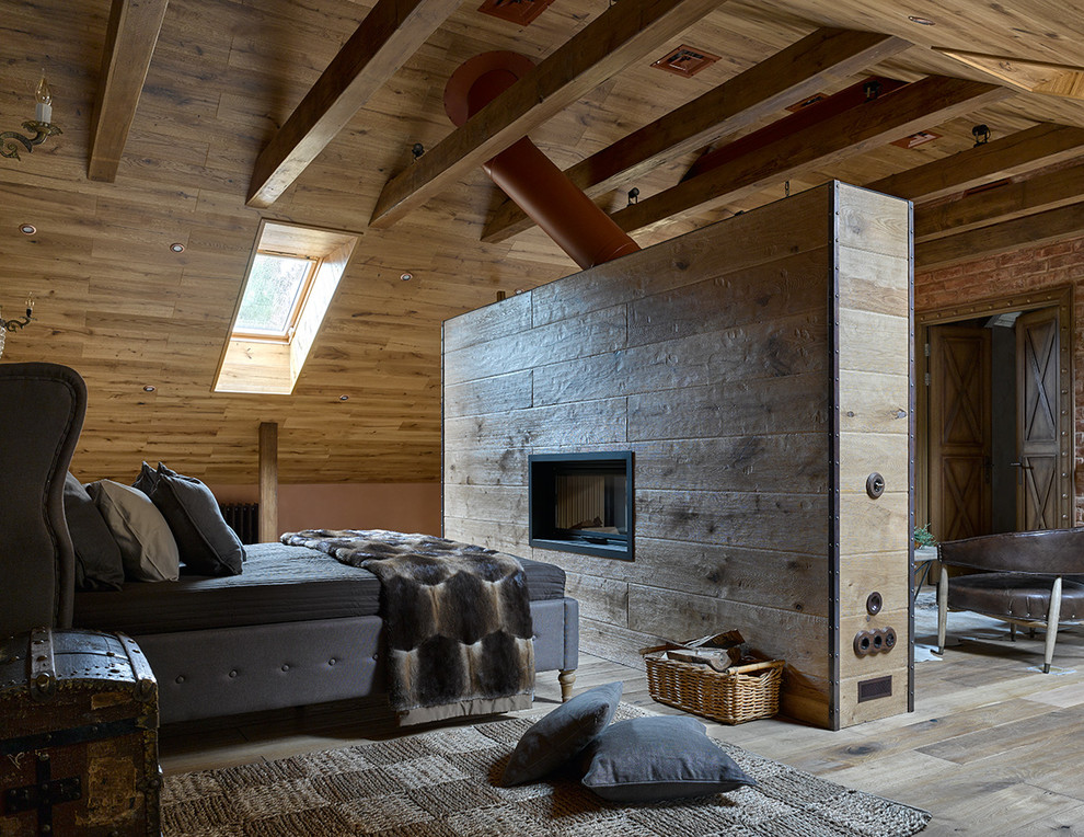 This is an example of a rural master loft bedroom in Moscow with brown walls, medium hardwood flooring, a two-sided fireplace and a tiled fireplace surround.