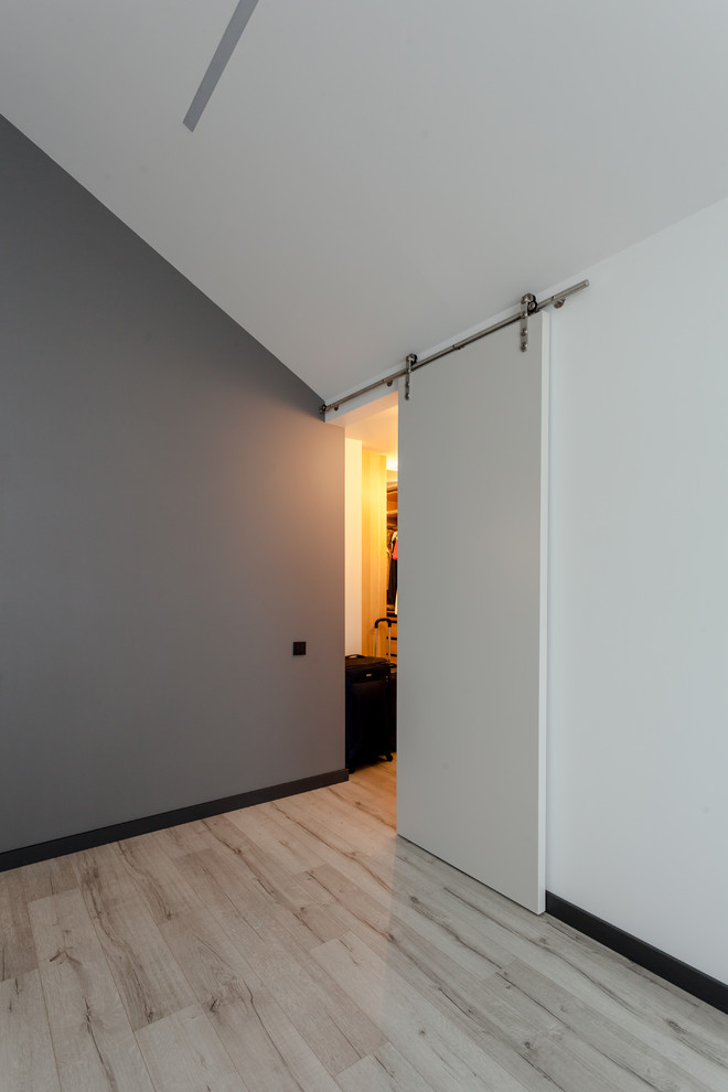 Imagen de dormitorio principal actual de tamaño medio con paredes blancas, suelo laminado y suelo beige