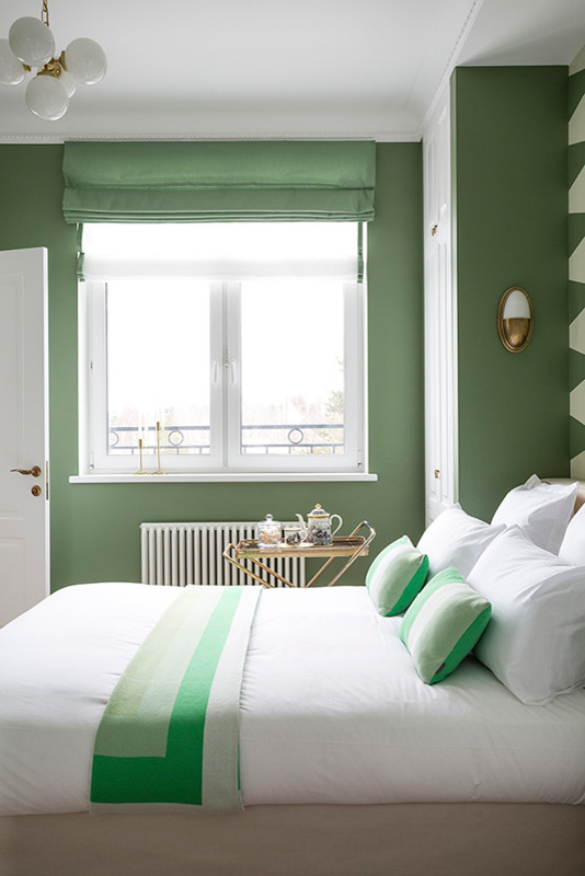 Foto de dormitorio principal actual de tamaño medio sin chimenea con paredes verdes, suelo de madera en tonos medios y suelo marrón