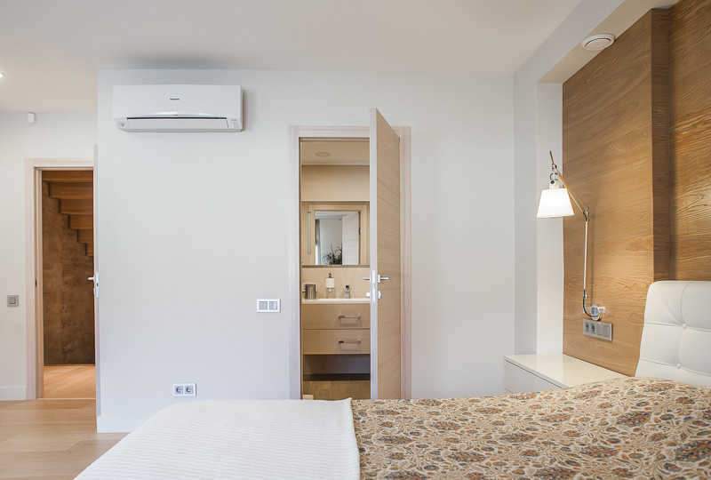 Diseño de dormitorio principal actual con paredes blancas y suelo de madera clara