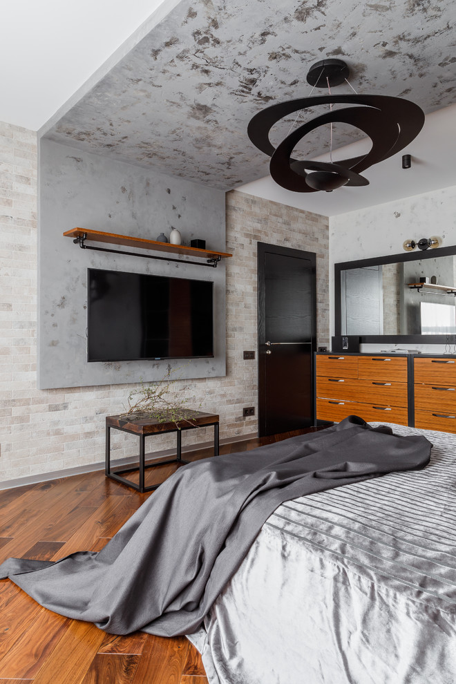Idée de décoration pour une chambre parentale urbaine de taille moyenne avec un mur gris, un sol en bois brun et un sol marron.