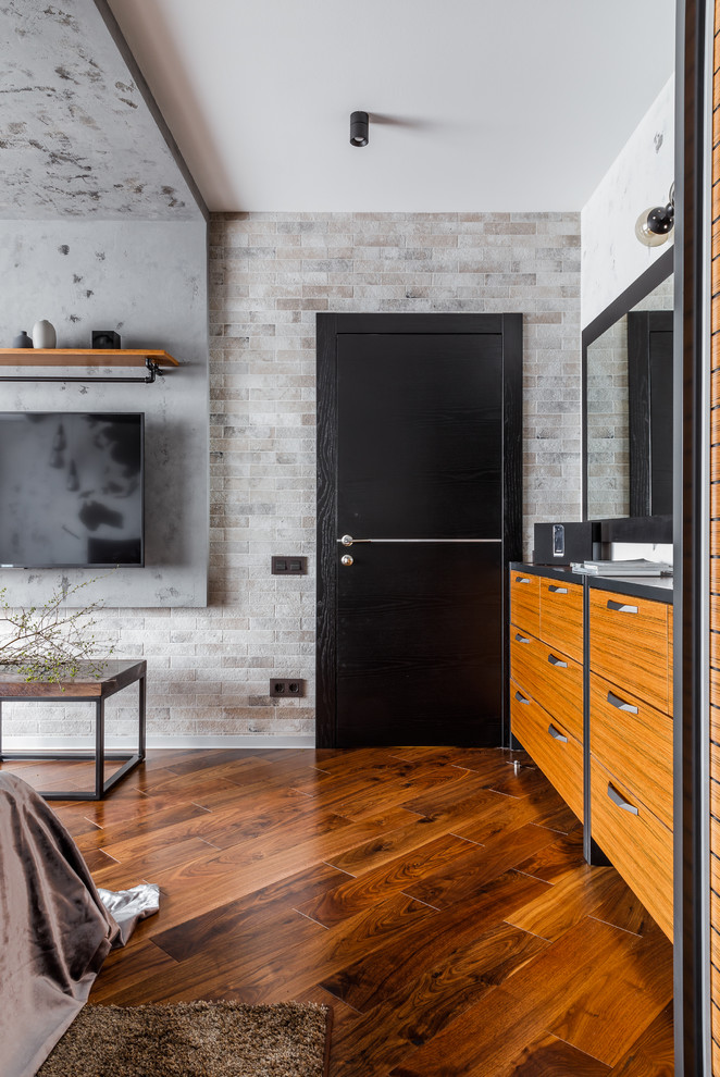 Imagen de dormitorio principal urbano de tamaño medio con paredes grises, suelo de madera en tonos medios y suelo marrón