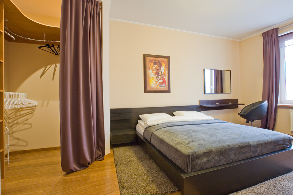 Foto de dormitorio actual pequeño con suelo laminado y suelo marrón